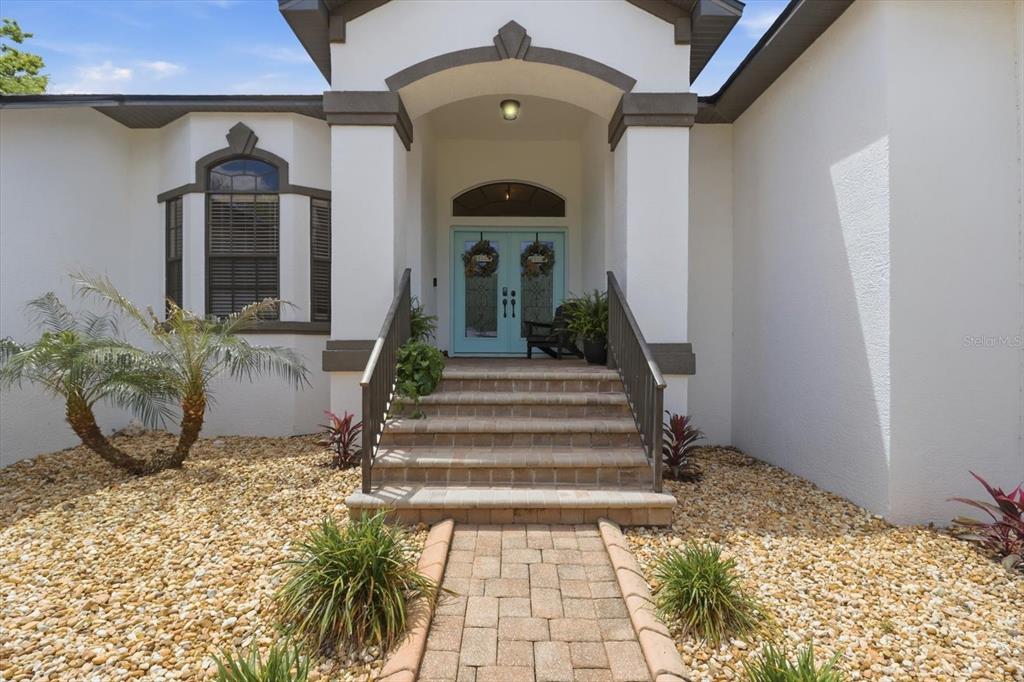A paved walkway leads to the front entrance of a house with light blue doors — 11870 W WATERWAY DRIVE, HOMOSASSA, FL