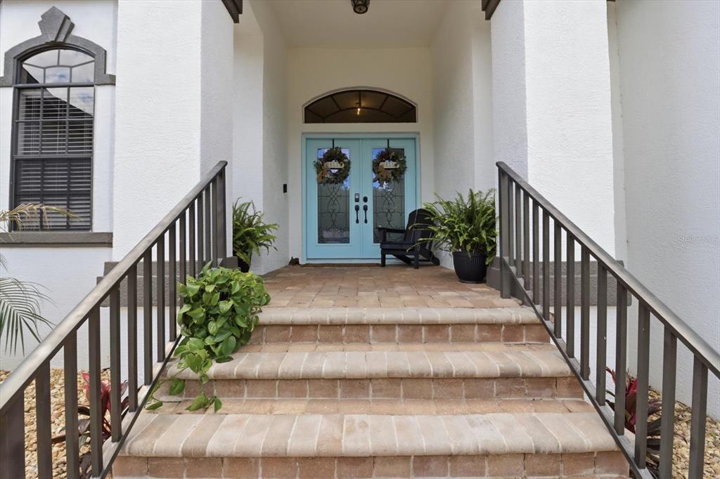 A front entryway features light blue double doors, brick stairs, and dark metal railings — 11870 W WATERWAY DRIVE, HOMOSASSA, FL
