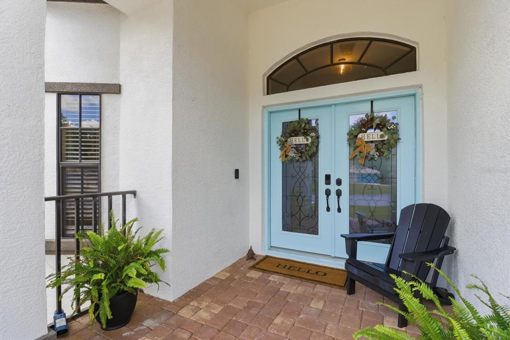 A light blue double front door with glass inserts and wreaths sits on a paved porch — 11870 W WATERWAY DRIVE, HOMOSASSA, FL