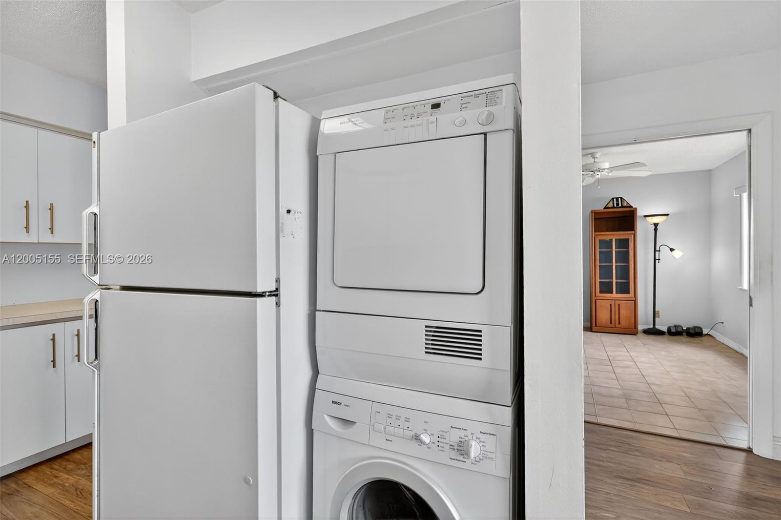 A white refrigerator and a stacked Bosch washer-dryer unit are located in a kitchen area — 13950 Via Flora # D, Delray Beach FL 33484, DELRAY BEACH, FL