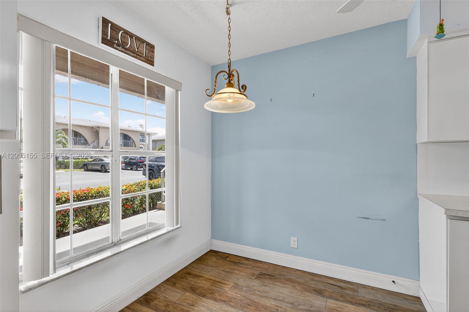 A dining area features a light blue accent wall, wood-look flooring, and a pendant light — 13950 Via Flora # D, Delray Beach FL 33484, DELRAY BEACH, FL