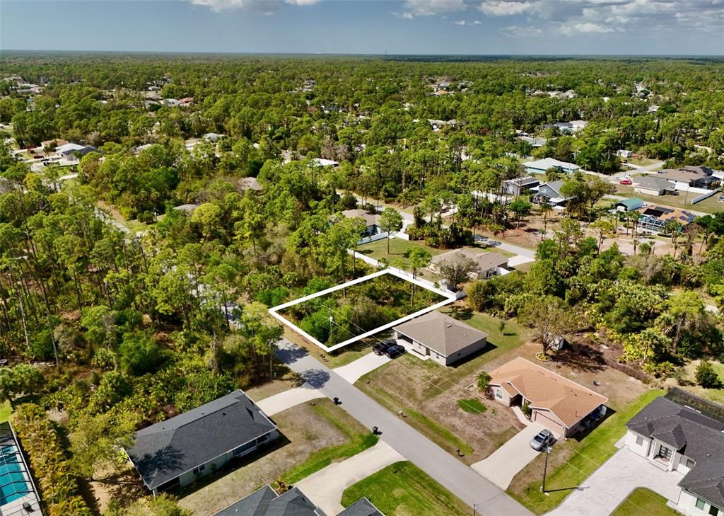 An aerial view shows a vacant, rectangular residential lot surrounded by trees and suburban homes — APOLLO AVENUE, NORTH PORT, FL
