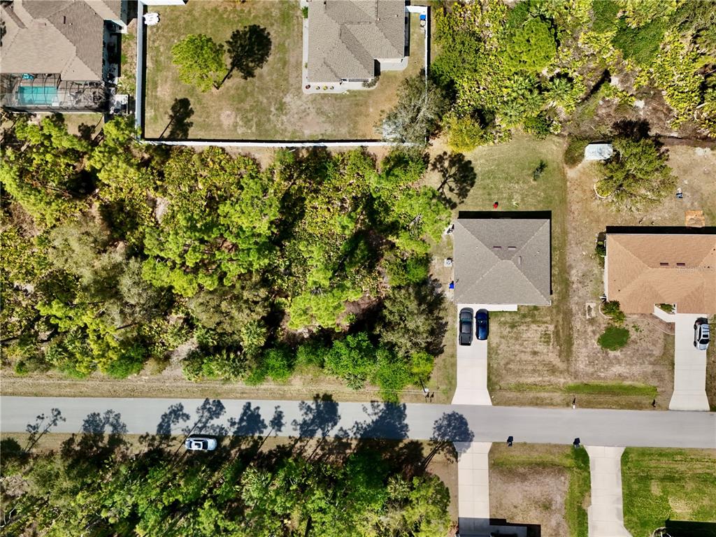 This aerial view shows several houses with driveways and surrounding wooded areas — APOLLO AVENUE, NORTH PORT, FL