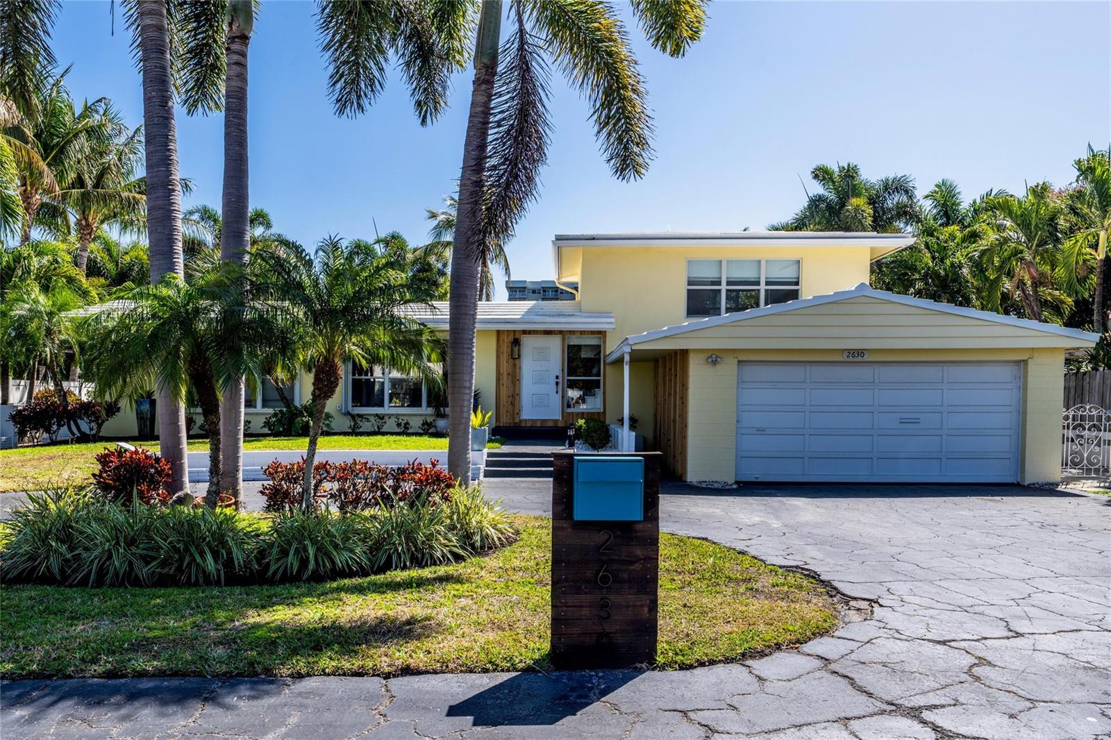 A yellow single-story house with a two-car garage and palm trees in the front yard — 2630 NE 25th Street, Lighthouse Point FL 33064, LIGHTHOUSE POINT, FL