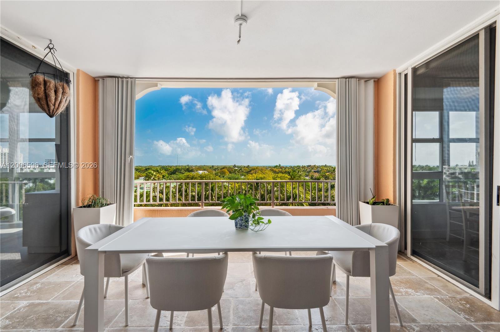 A dining table with six chairs sits on a covered balcony overlooking a lush landscape — 747 Crandon Blvd, Key Biscayne FL 33149, KEY BISCAYNE, FL