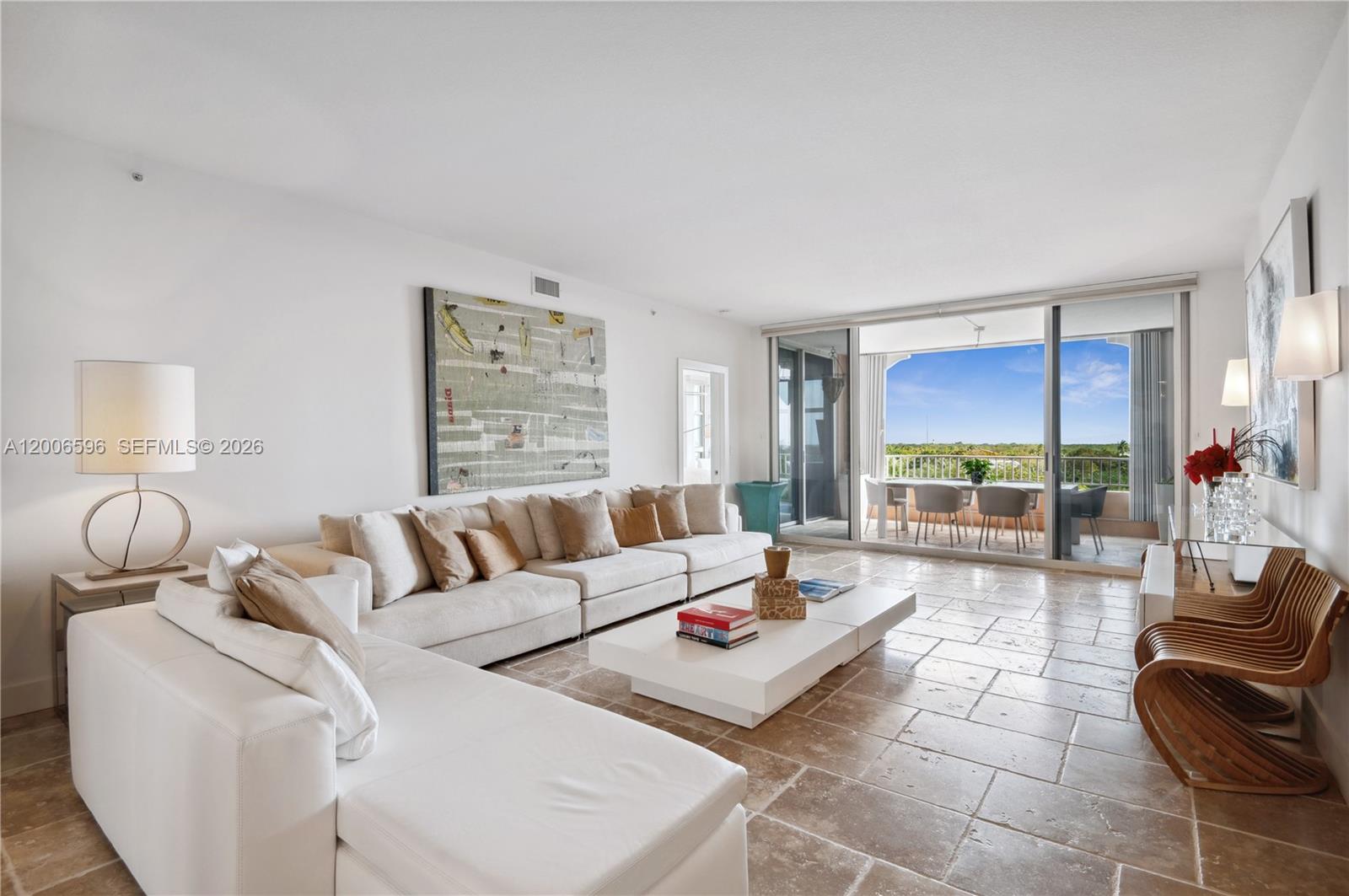 A living room with a white sectional sofa, stone tile floors, and a balcony view — 747 Crandon Blvd, Key Biscayne FL 33149, KEY BISCAYNE, FL