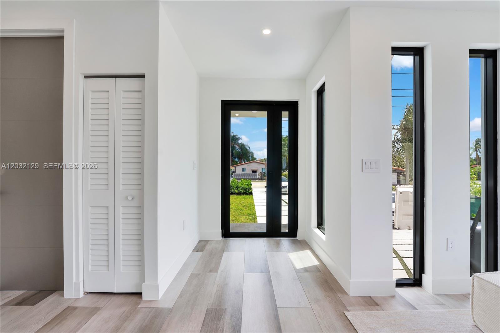 A bright entryway features white walls, light wood-look flooring, a closet, and a black-framed door — 2665 Johnson St, Hollywood FL 33020, HOLLYWOOD, FL