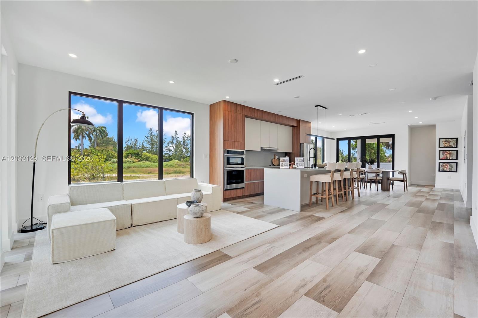An open-concept living room and kitchen feature light wood flooring and large floor-to-ceiling windows — 2665 Johnson St, Hollywood FL 33020, HOLLYWOOD, FL