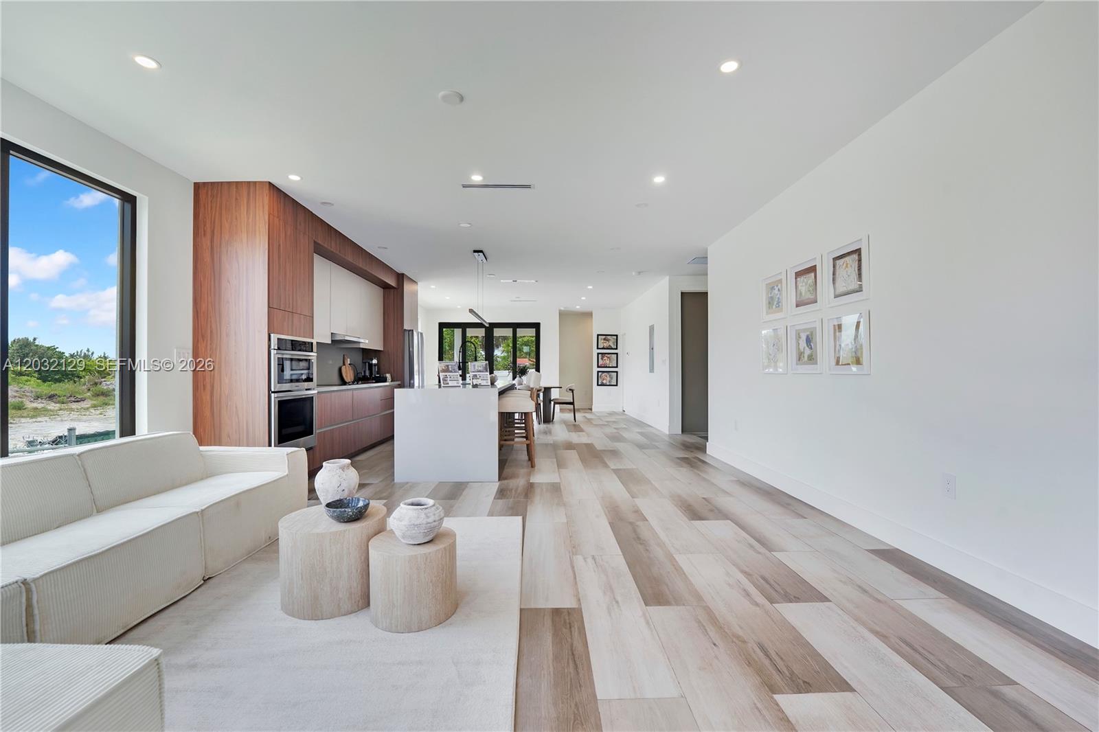 A modern open-concept living room and kitchen feature wood cabinetry, a white island, and flooring — 2665 Johnson St, Hollywood FL 33020, HOLLYWOOD, FL
