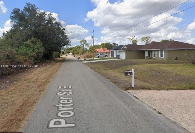 A paved street named Porter St E runs past a suburban house and wooded area — 820 Porter ST E, Lehigh Acres FL 33974, LEHIGH ACRES, FL