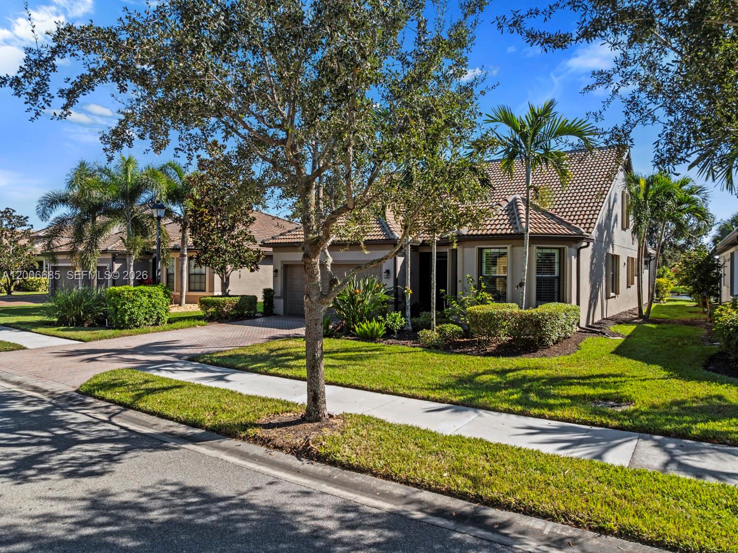 A single-story house with a tiled roof, brick driveway, and palm trees in the front yard — 6264 Victory Dr, Ave Maria FL 34142, AVE MARIA, FL