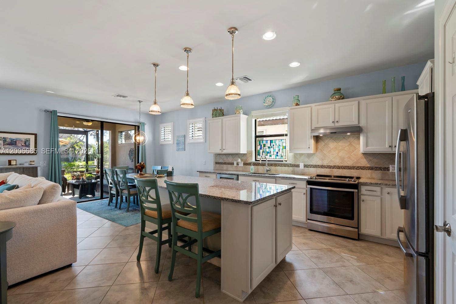 A kitchen with white cabinets, granite countertops, and an island with green chairs — 6264 Victory Dr, Ave Maria FL 34142, AVE MARIA, FL