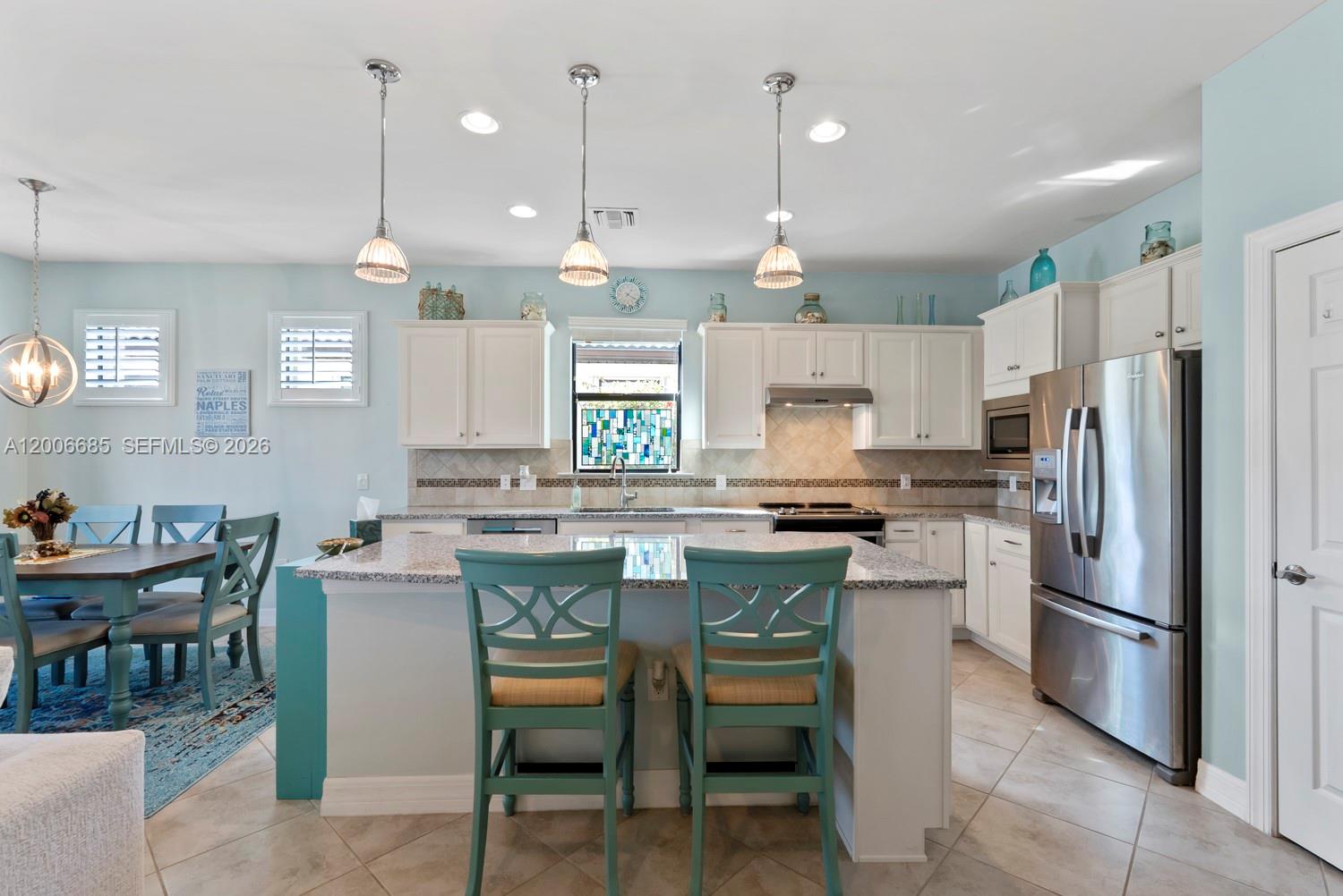 A kitchen features white cabinets, granite countertops, a central island, and light blue walls — 6264 Victory Dr, Ave Maria FL 34142, AVE MARIA, FL