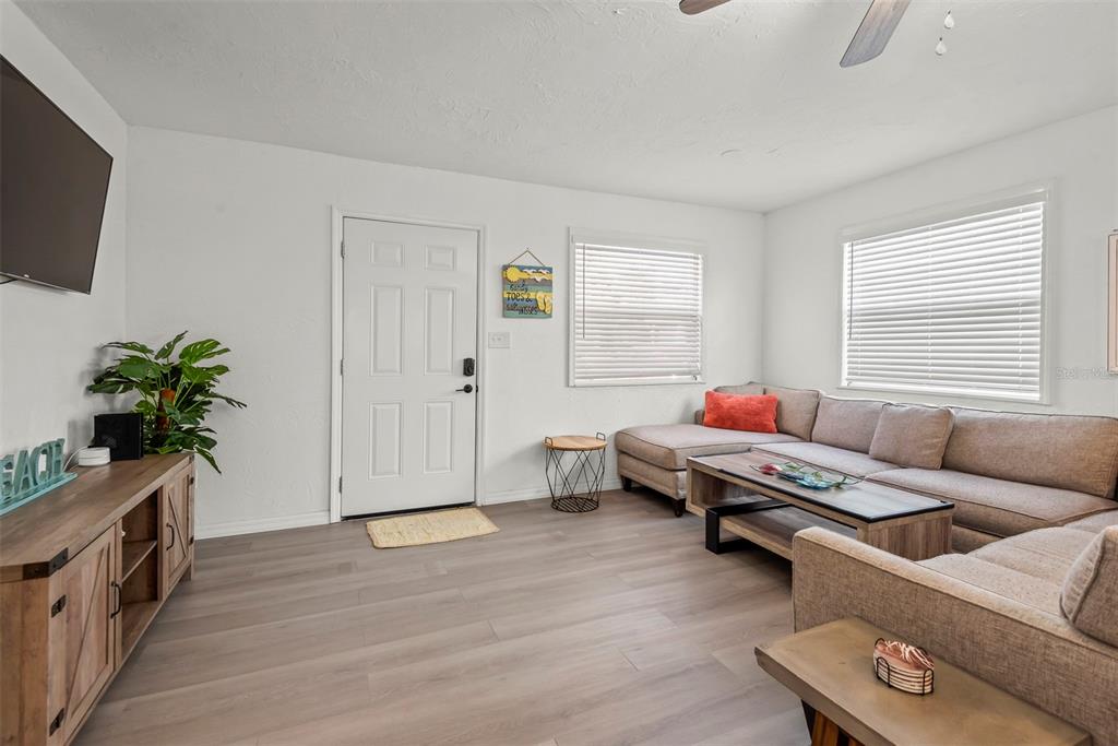A living room features light wood flooring, a sectional sofa, and a wooden media console — 5125 ISABELLE AVENUE, PORT ORANGE, FL