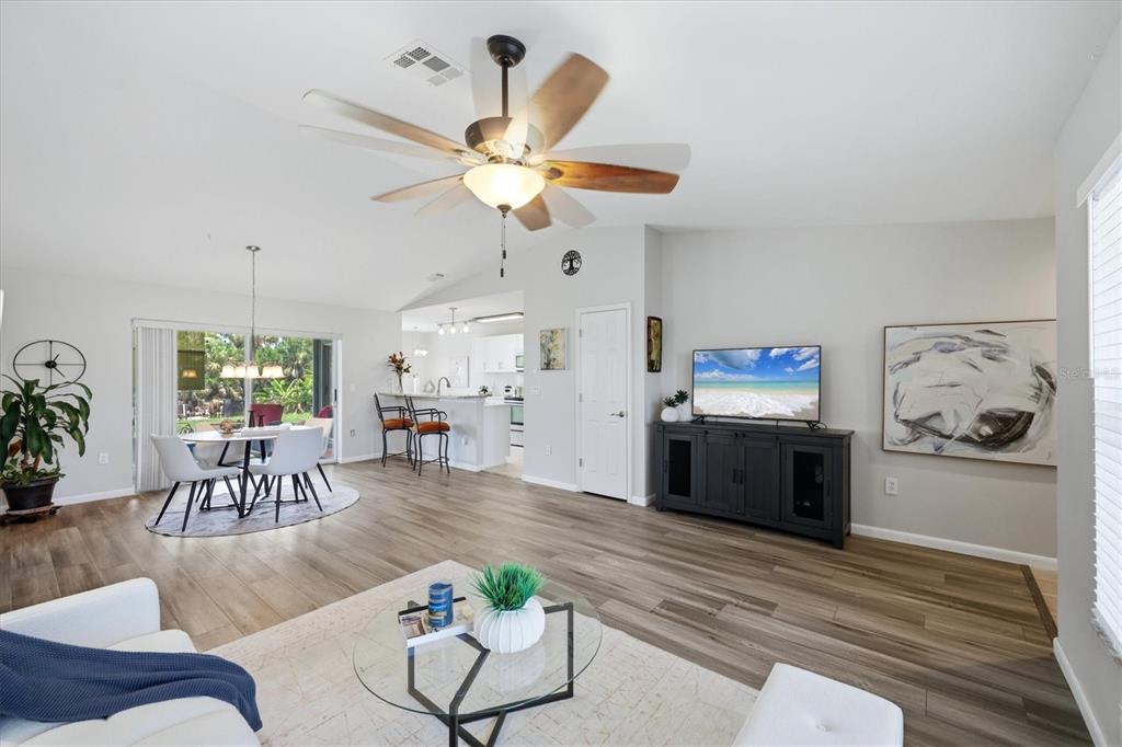 A bright, open-concept living area features wood-look flooring, a ceiling fan, and a kitchen island — 9084 PROSPECT AVENUE, ENGLEWOOD, FL
