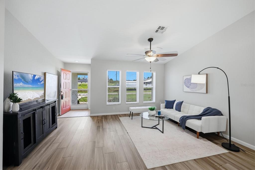 A living room features light wood floors, a white sofa, and a black media console — 9084 PROSPECT AVENUE, ENGLEWOOD, FL