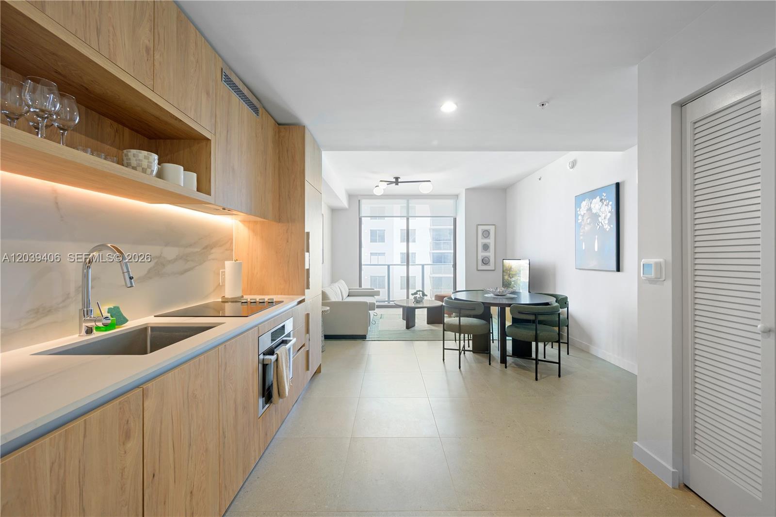 A modern kitchen with light wood cabinetry opens into a dining area and living room — 11 NE 6th St # 2411, Miami FL 33132, MIAMI, FL
