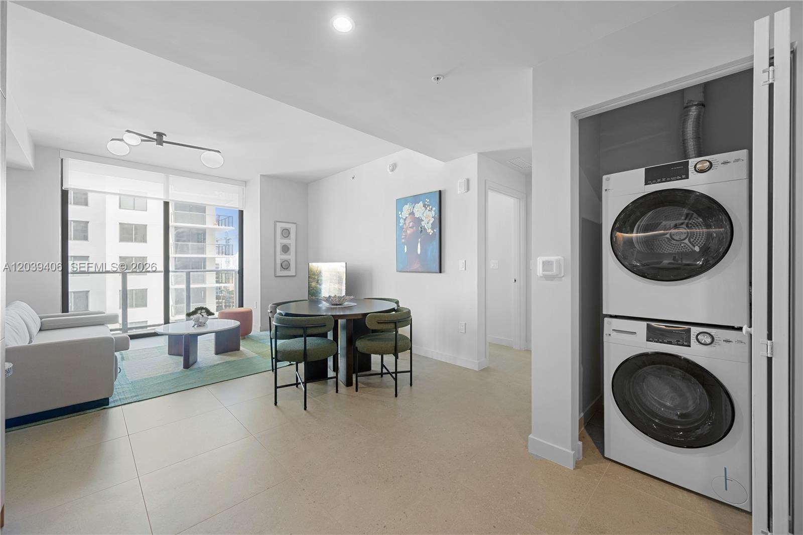 A modern living and dining area features a stacked washer-dryer unit and floor-to-ceiling windows — 11 NE 6th St # 2411, Miami FL 33132, MIAMI, FL