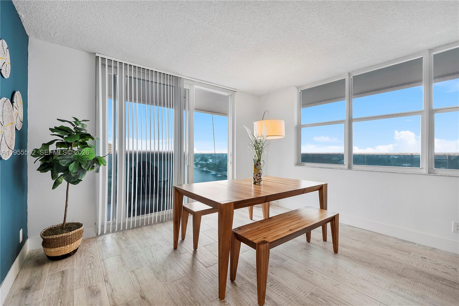 A dining area features a wooden table and benches, light tile floors, and balcony views — 2639 N Riverside Dr # 806, Pompano Beach FL 33062, POMPANO BEACH, FL