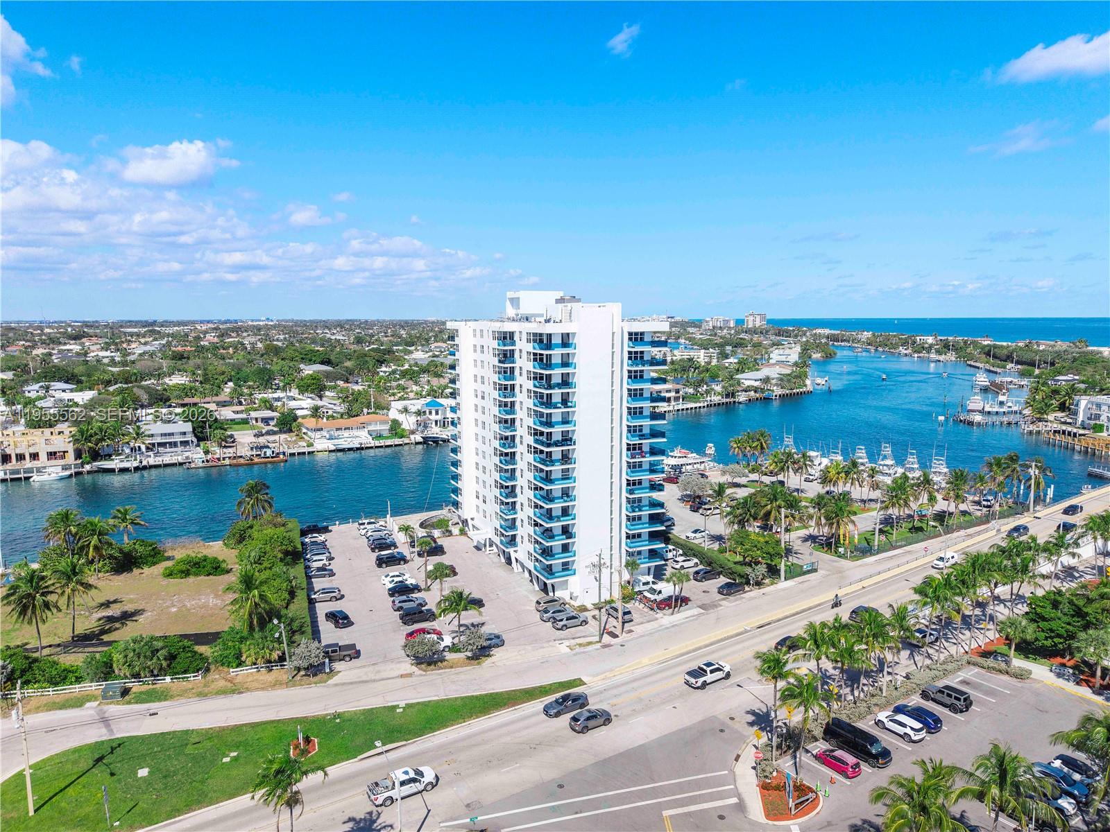 An aerial view shows a tall white apartment building situated next to a waterway — 2639 N Riverside Dr # 806, Pompano Beach FL 33062, POMPANO BEACH, FL