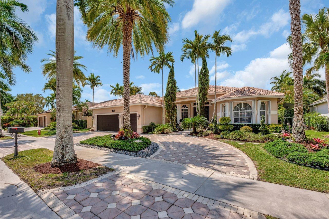 A single-story house with a paved driveway, a two-car garage, and several tall palm trees — 2491 Eagle Run Drive, Weston FL 33327, WESTON, FL