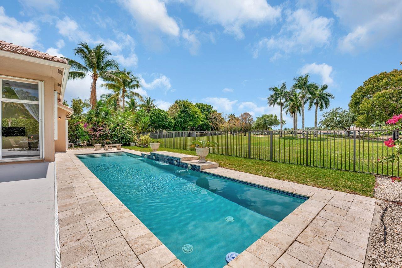 A rectangular swimming pool with a water feature sits on a patio beside a house — 2491 Eagle Run Drive, Weston FL 33327, WESTON, FL