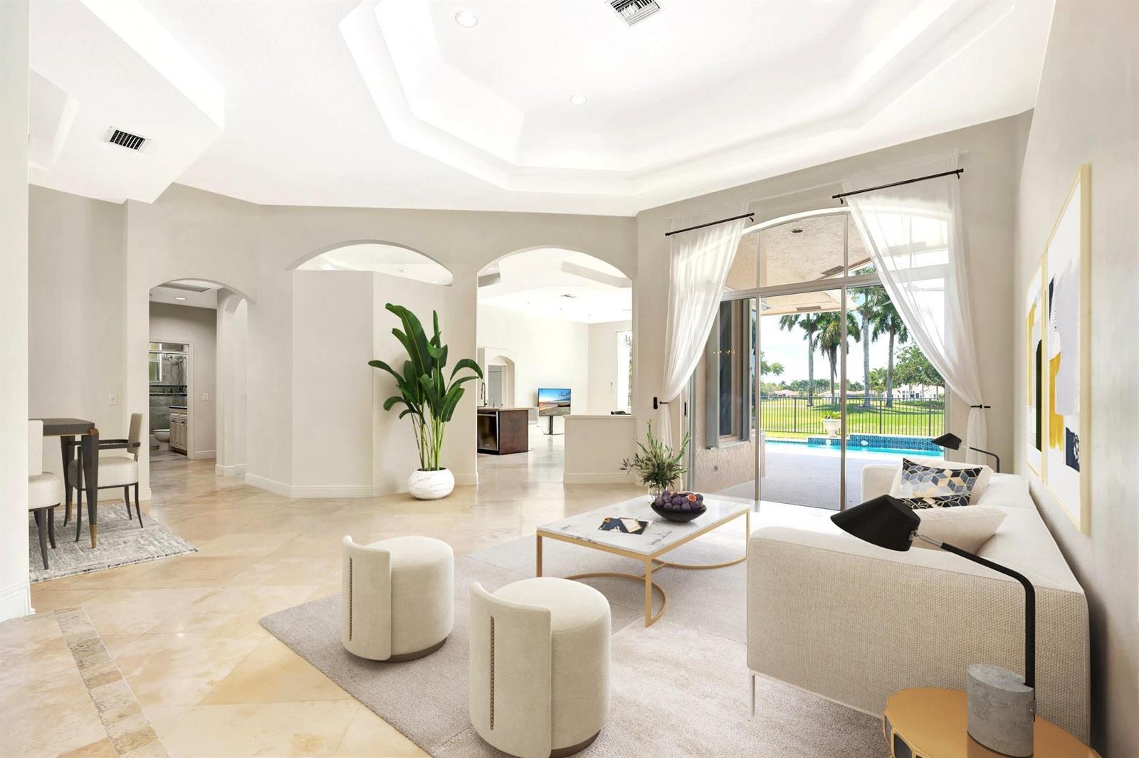 A bright living room features a tray ceiling, marble coffee table, and sliding doors to a pool — 2491 Eagle Run Drive, Weston FL 33327, WESTON, FL