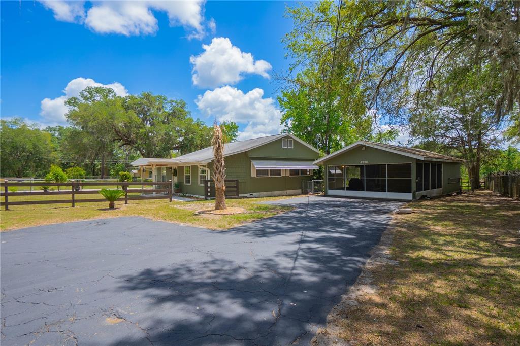 A green house with a detached screened-in garage sits on a large, grassy lot — 4556 E SHOREWOOD DRIVE, HERNANDO, FL
