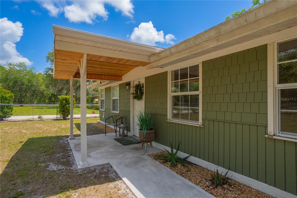 A green-sided house features a covered concrete porch with a wooden ceiling and walkway — 4556 E SHOREWOOD DRIVE, HERNANDO, FL