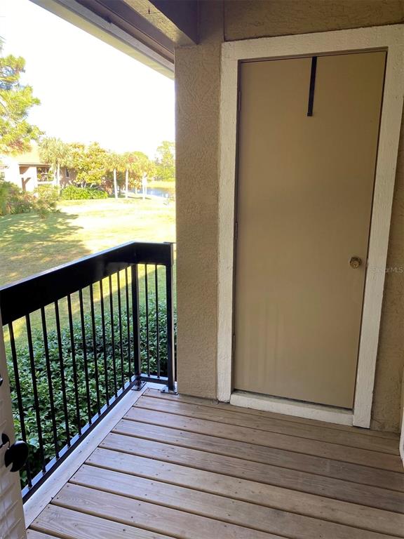 A balcony with a wooden deck, black metal railing, and a beige storage closet door — 4041 CROCKERS LAKE BOULEVARD UNIT 24, SARASOTA, FL