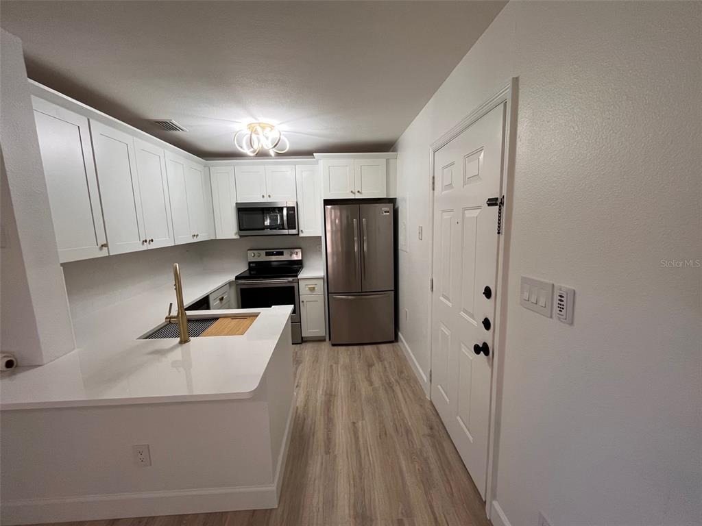 A kitchen features white cabinets, stainless steel appliances, and a peninsula with a sink — 4041 CROCKERS LAKE BOULEVARD UNIT 24, SARASOTA, FL
