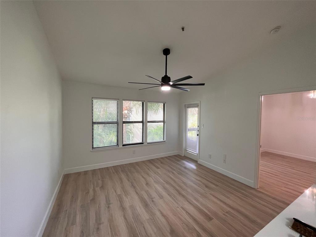 An empty room features light wood-look flooring, a ceiling fan, and a glass-paned door — 4041 CROCKERS LAKE BOULEVARD UNIT 24, SARASOTA, FL