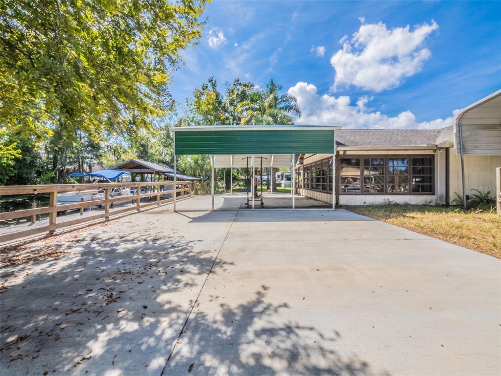 A concrete driveway leads to a metal carport attached to a house beside a canal — 55746 CARROL STREET, ASTOR, FL
