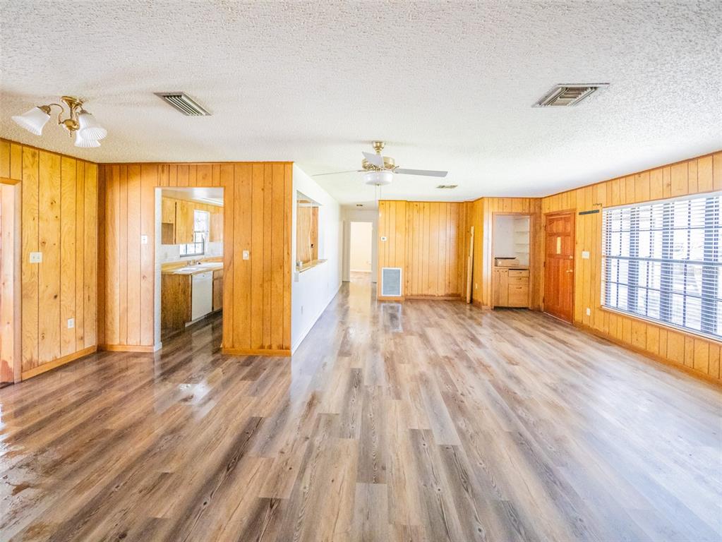 A living room features wood-paneled walls, wood-look flooring, and a ceiling fan — 55746 CARROL STREET, ASTOR, FL