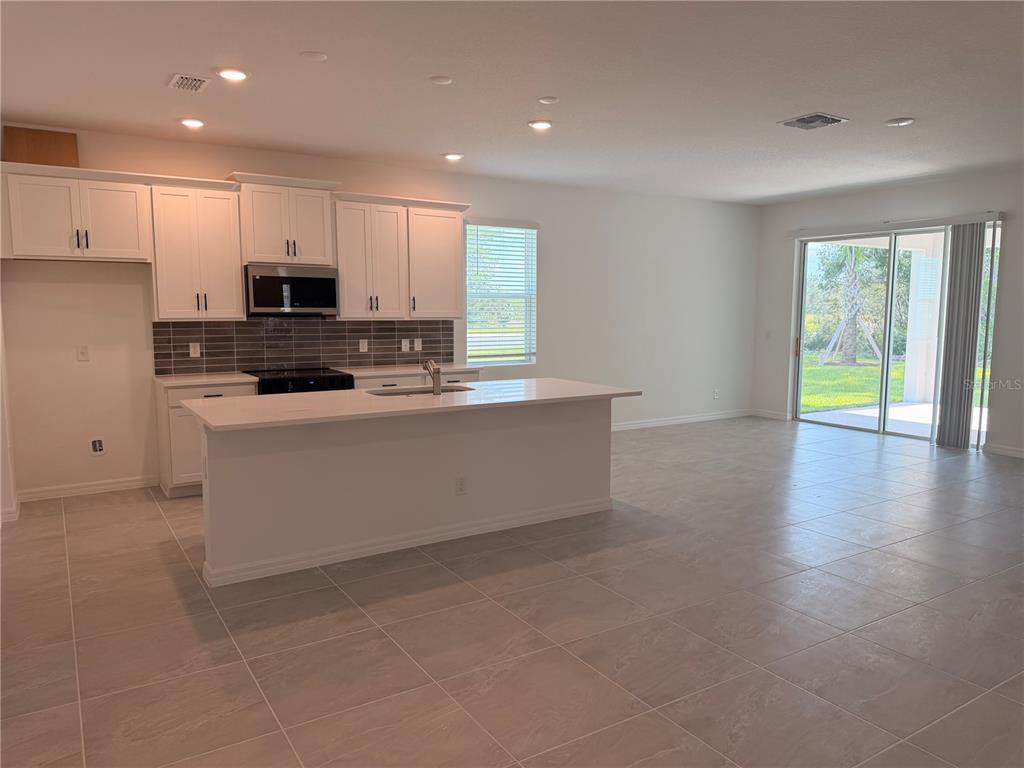 A single-story house with a gray stucco exterior, a two-car garage, and a paver driveway — 744 FARFIELDS STREET, DELAND, FL