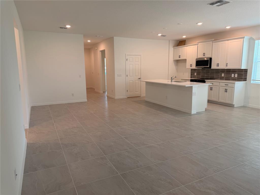 A single-story house with a light gray exterior, a two-car garage, and a paved driveway — 744 FARFIELDS STREET, DELAND, FL