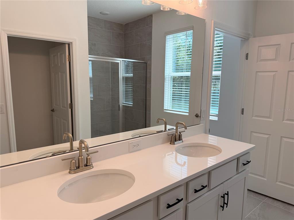 A kitchen features white cabinets, a stainless steel microwave, and a dark tile backsplash — 744 FARFIELDS STREET, DELAND, FL