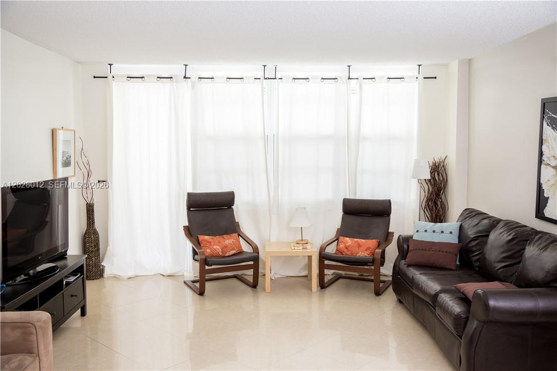 A living room features a dark leather sofa, two armchairs, and white curtains — 3725 S Ocean Dr # 1003, Hollywood FL 33019, HOLLYWOOD, FL