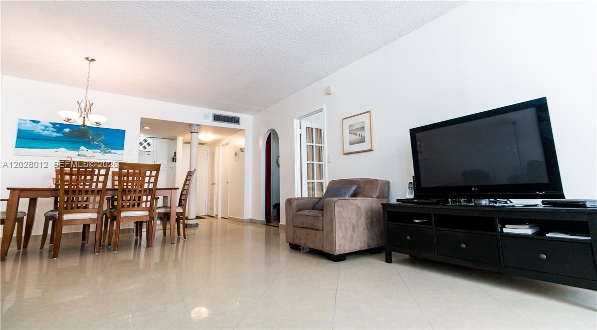 A living and dining area features tile flooring, a television console, and a brown armchair — 3725 S Ocean Dr # 1003, Hollywood FL 33019, HOLLYWOOD, FL