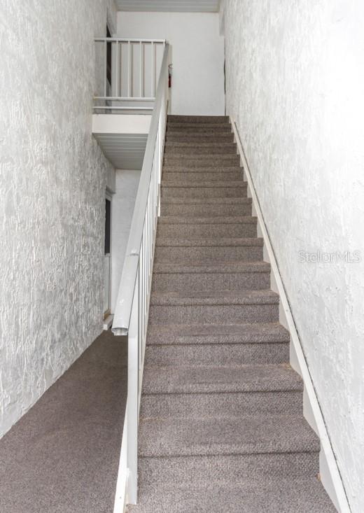 A carpeted staircase with a white metal railing leads to an upper landing — 359 S MCMULLEN BOOTH ROAD UNIT 122, CLEARWATER, FL