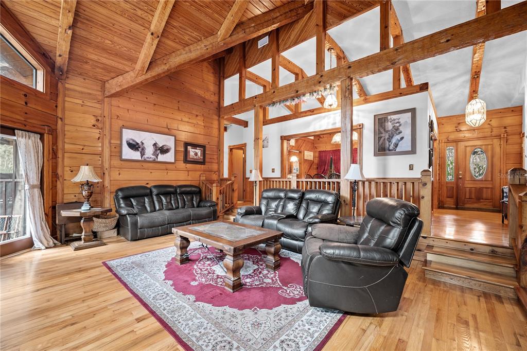 A rustic living room features wood-paneled walls, vaulted ceilings with exposed beams, and leather furniture — 6967 SHARRON ROAD, GREEN COVE SPRINGS, FL