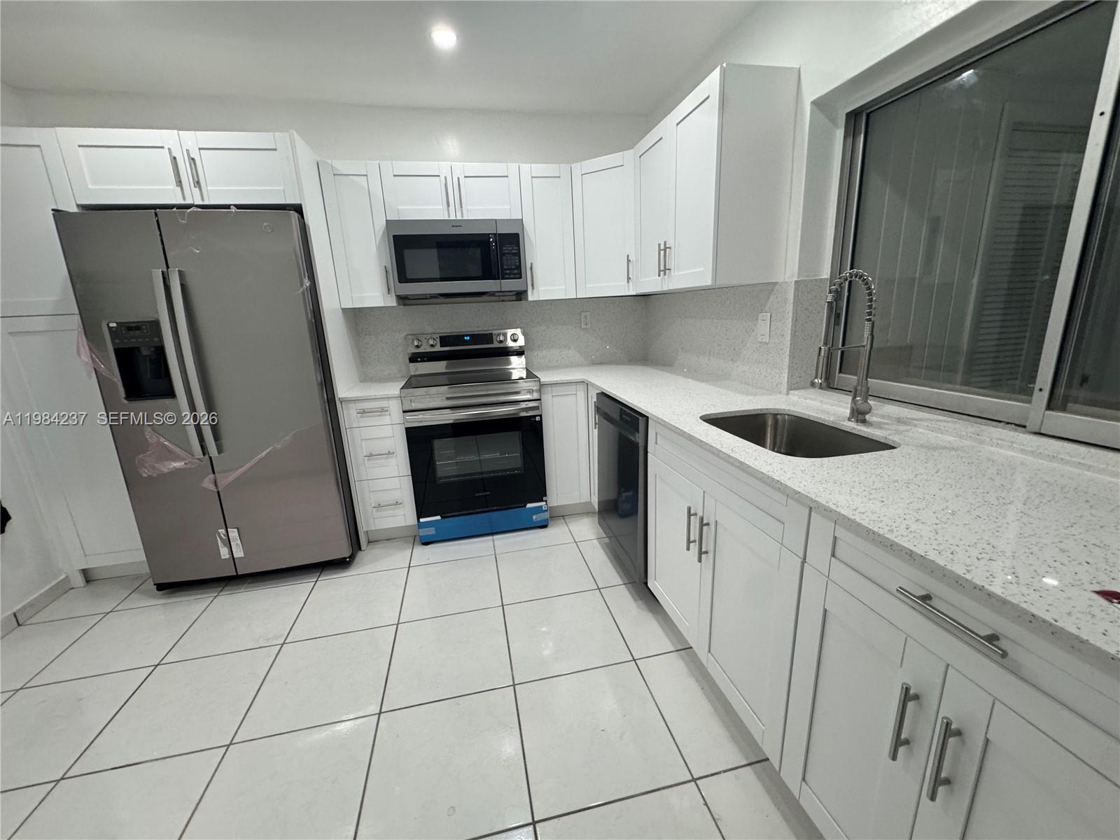 A kitchen features white cabinets, stainless steel appliances, and speckled white countertops — 11234 SW 169th St # V3443, Miami FL 33157, MIAMI, FL