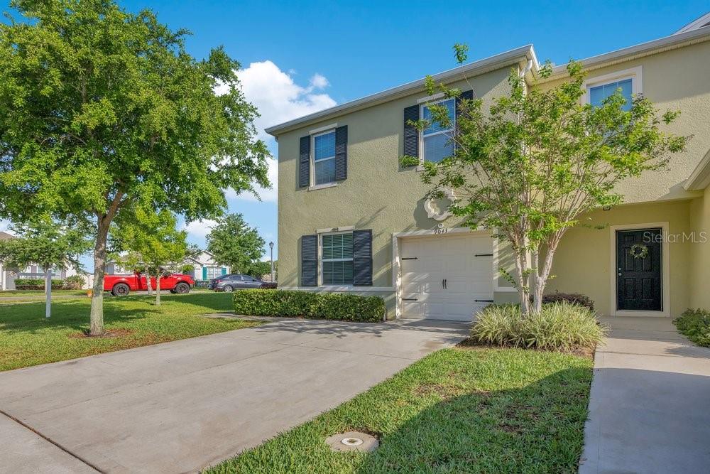 A two-story townhouse exterior features a concrete driveway, a single-car garage, and green landscaping — 9043 CARLOTTA WAY, KISSIMMEE, FL