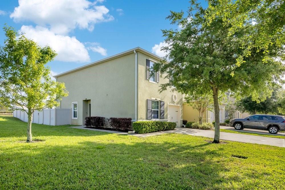 A two-story light green stucco house with a driveway and a side yard — 9043 CARLOTTA WAY, KISSIMMEE, FL