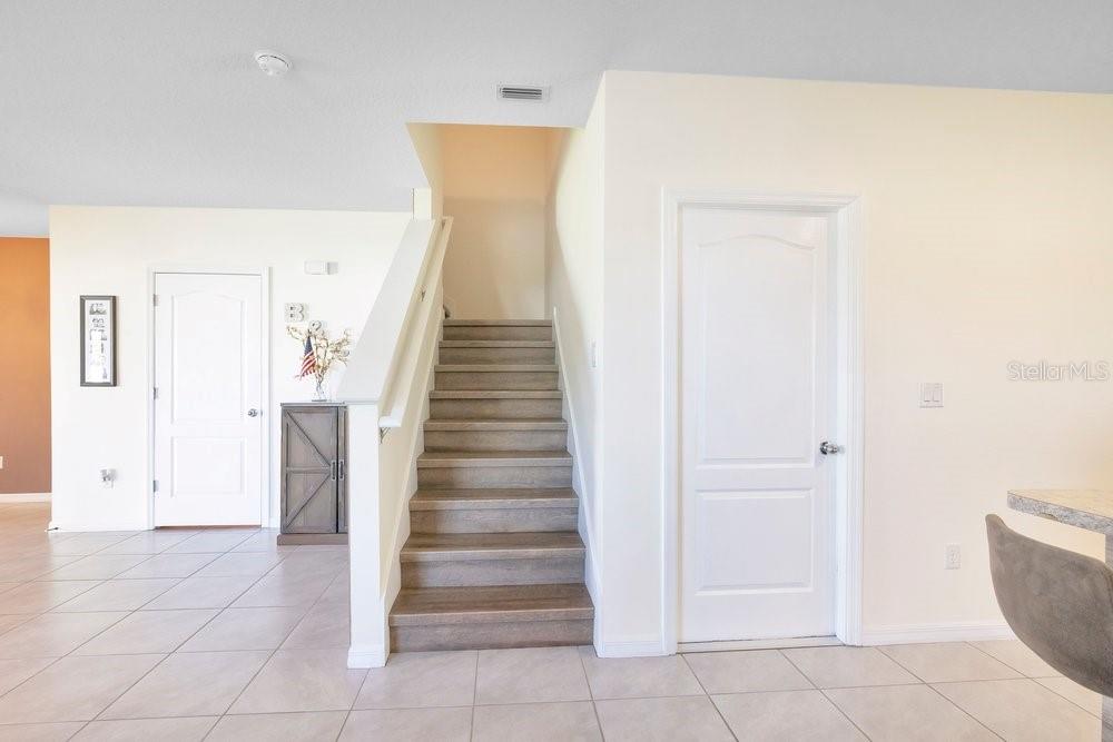 A staircase with wood-look treads sits between two white doors in a tiled room — 9043 CARLOTTA WAY, KISSIMMEE, FL