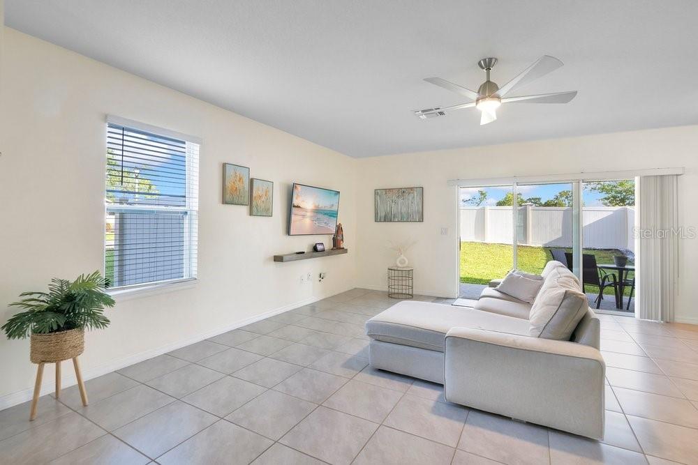 A living room with light tile floors, a sectional sofa, and a sliding glass door — 9043 CARLOTTA WAY, KISSIMMEE, FL