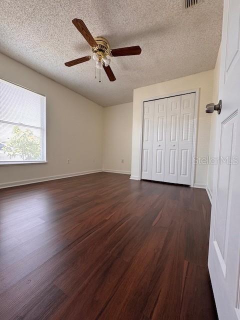A bedroom features dark wood-look flooring, a ceiling fan, and a white bifold closet door — 2405 LINCOLNSHIRE COURT, KISSIMMEE, FL