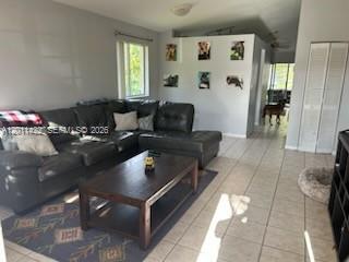 The exterior of a yellow house features a screened-in patio and two green trash bins — 450 SE 30th Dr, Homestead FL 33033, HOMESTEAD, FL