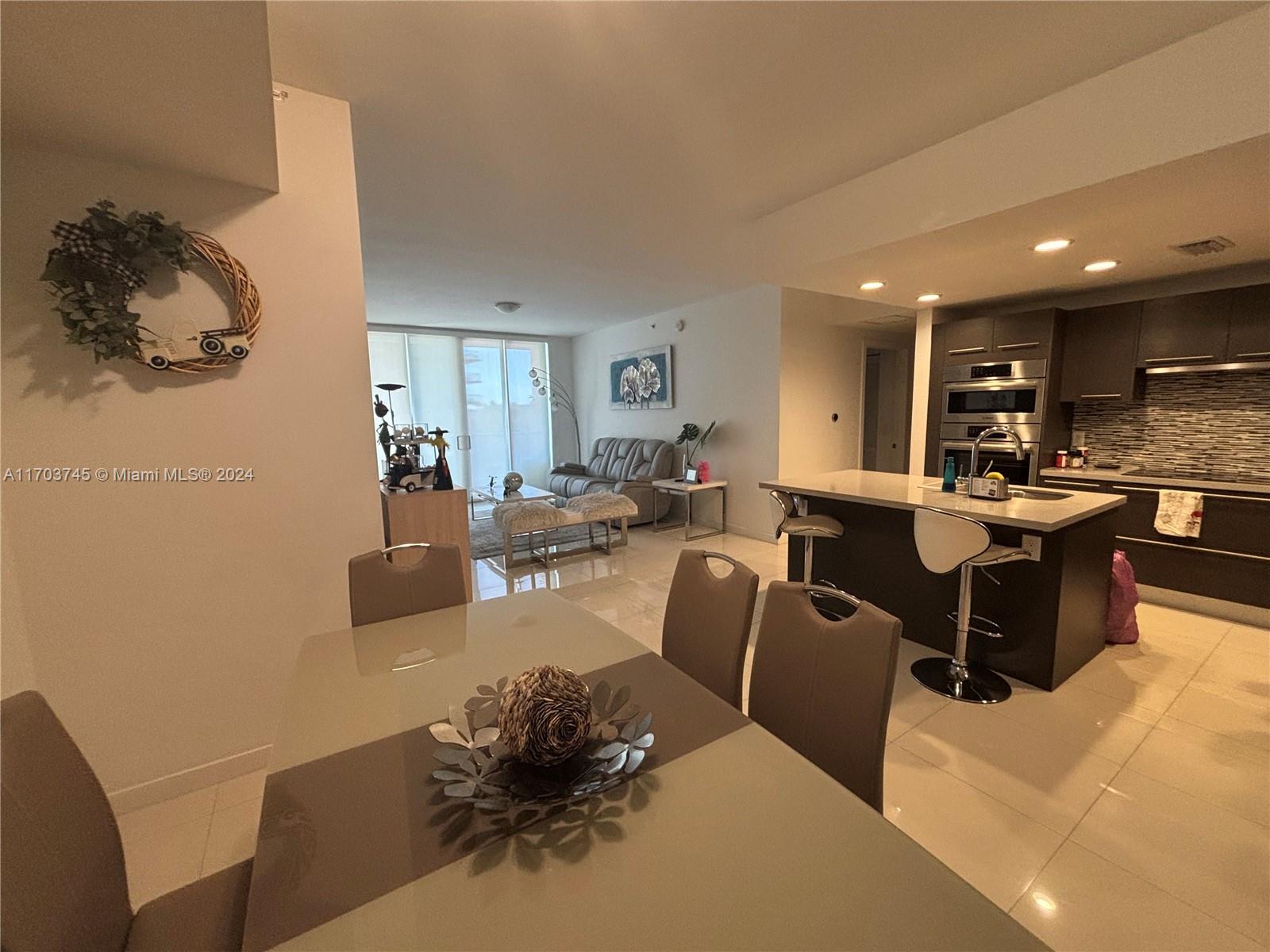 An open-concept living area features a dining table, kitchen island, and a sofa — 7825 NW 107th Ave # 310, Doral FL 33178, DORAL, FL