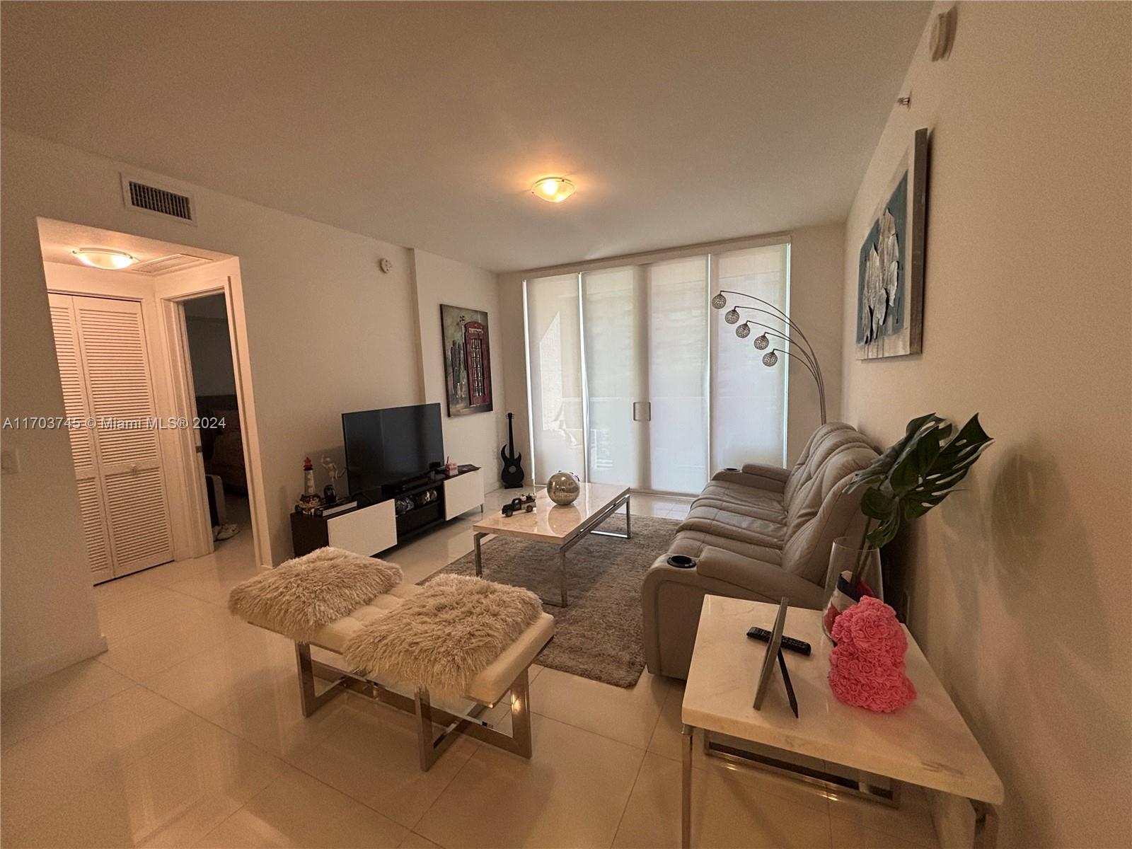 A living room features a grey sofa, a coffee table, a television, and tile flooring — 7825 NW 107th Ave # 310, Doral FL 33178, DORAL, FL